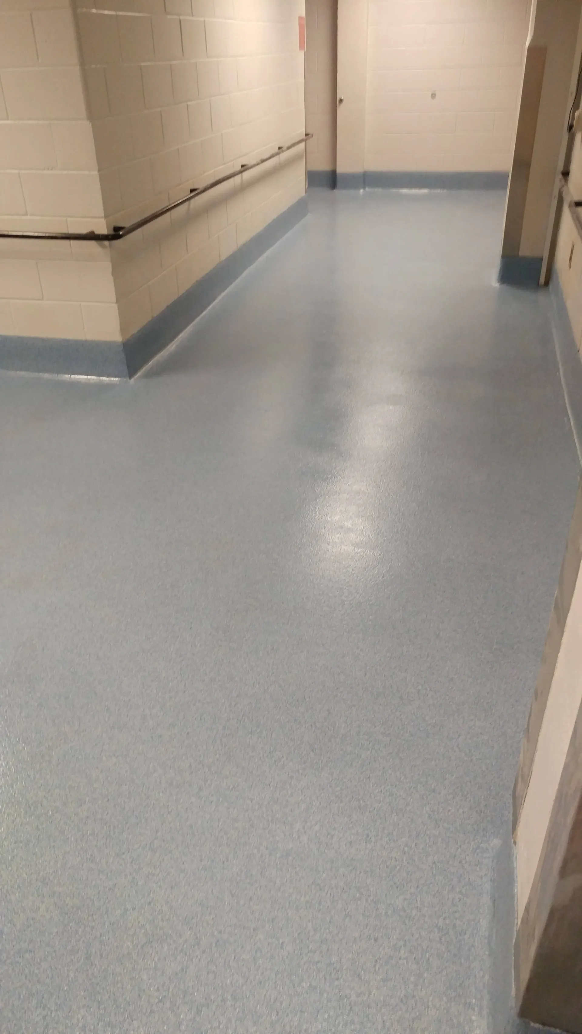 A hallway with a blue floor and a white wall.