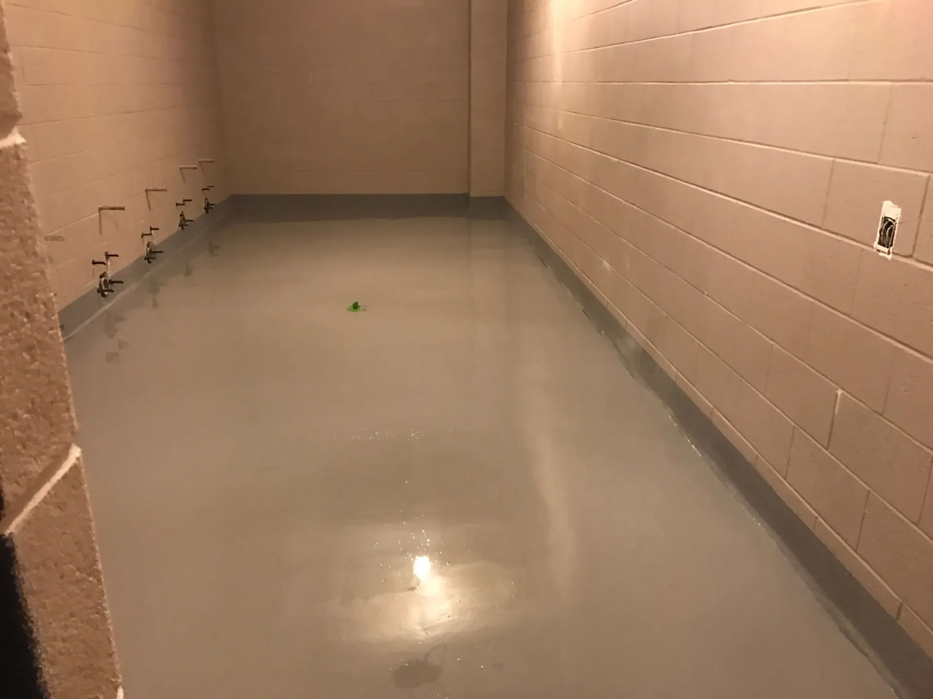 A very long room with a concrete floor and brick walls.