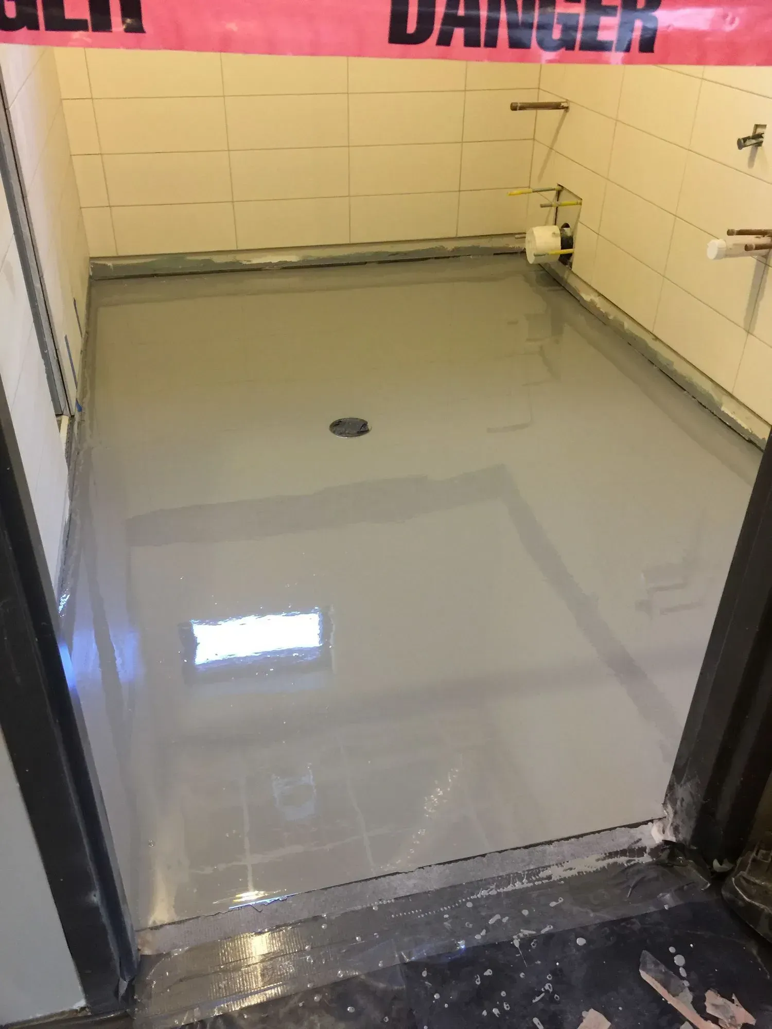 A room with a concrete floor and a danger sign on the wall.