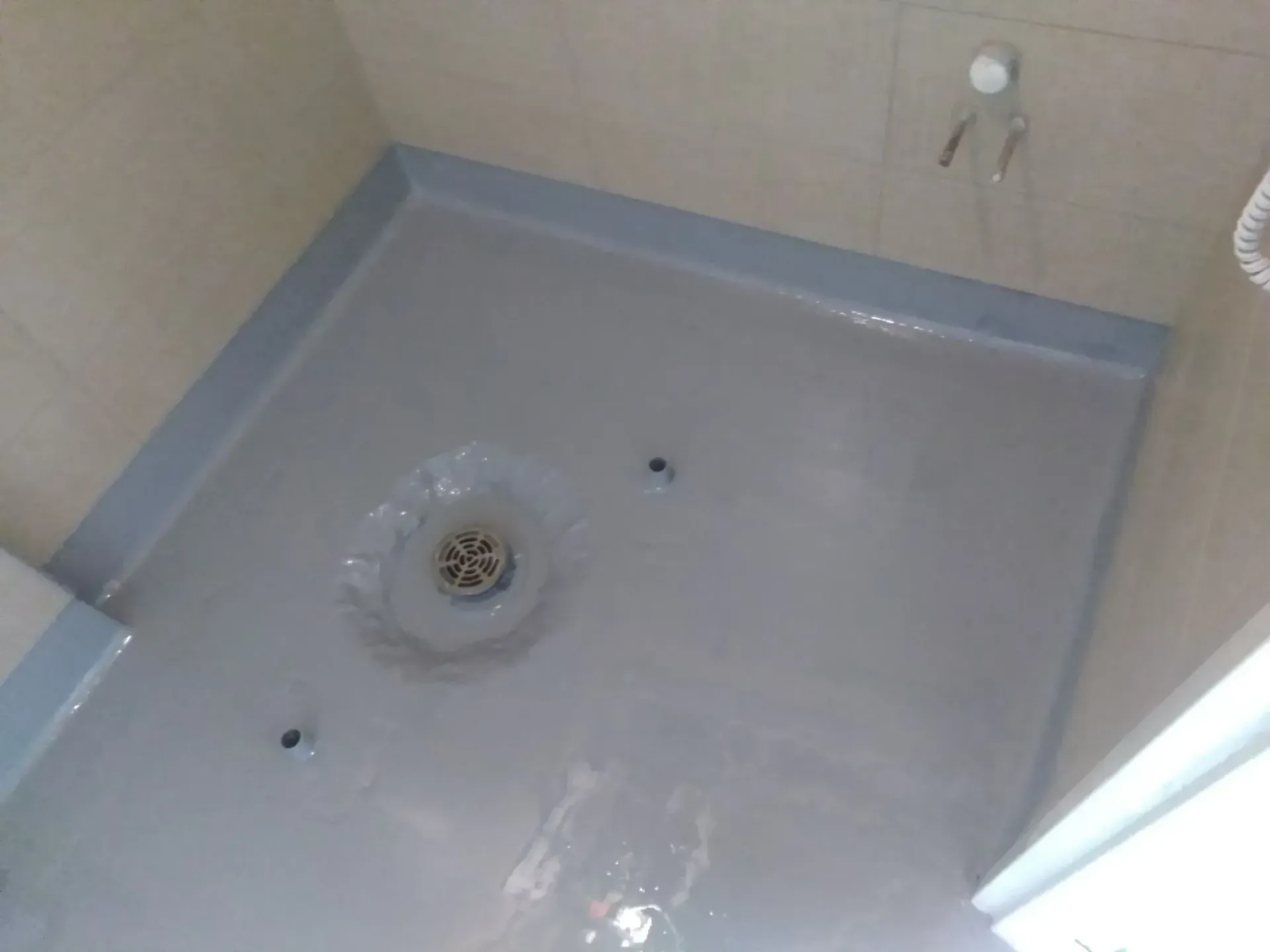 A bathroom floor with a drain in the middle of it.