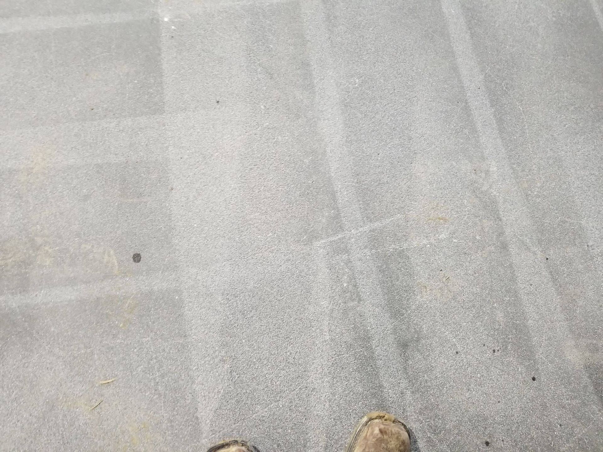 A person 's feet are standing on a concrete floor.