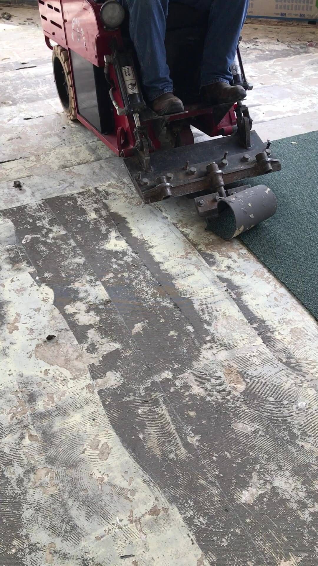 A person is riding a lawn mower on a concrete floor.