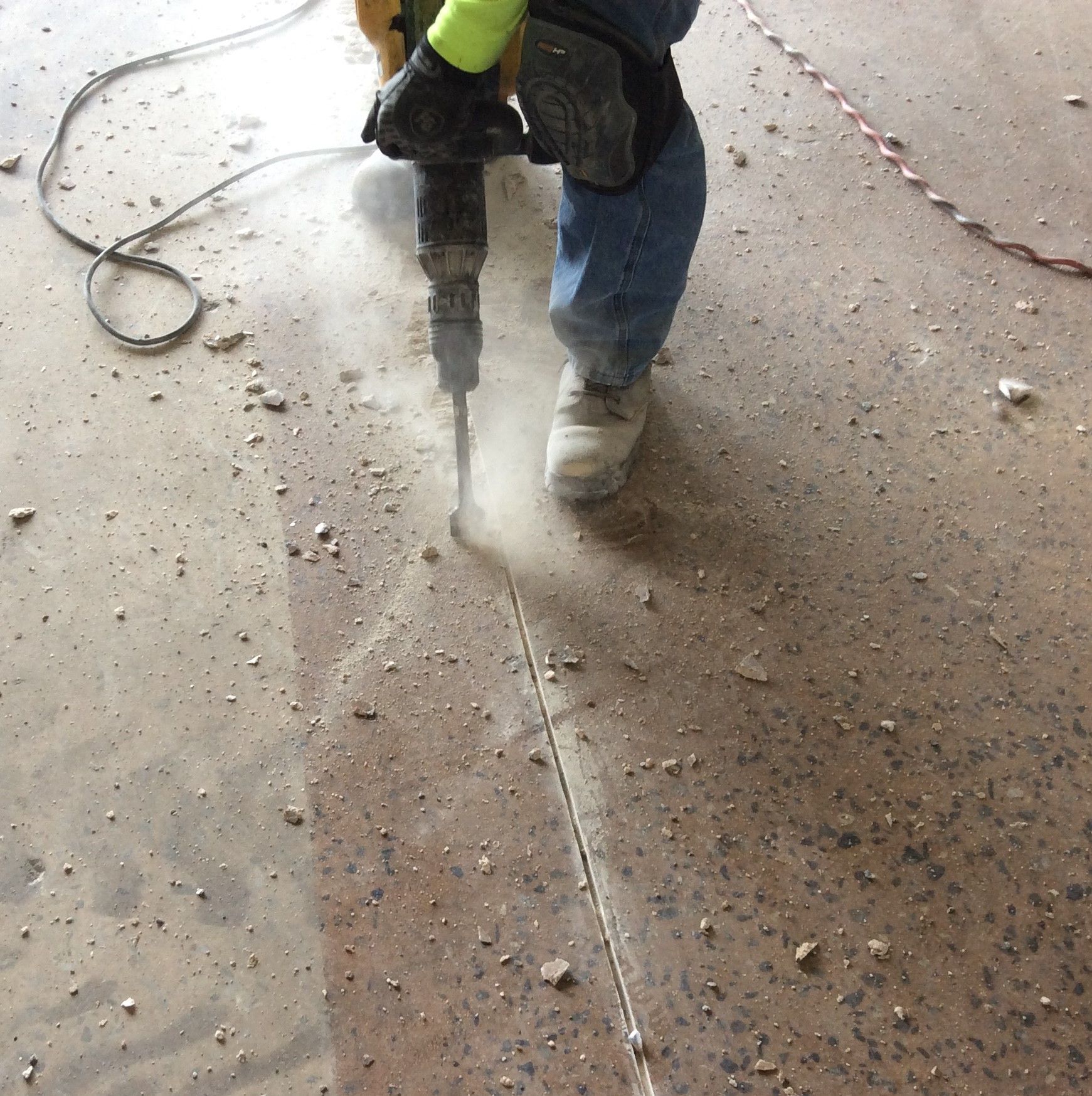 A person is using a hammer on a concrete floor