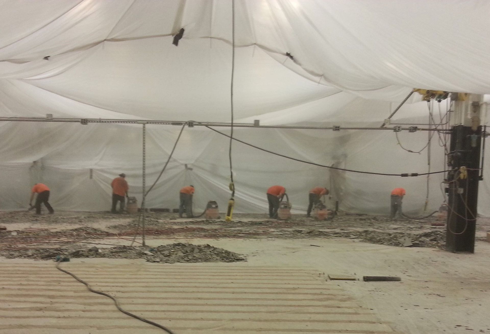 A group of people are working in a building under a tarp.