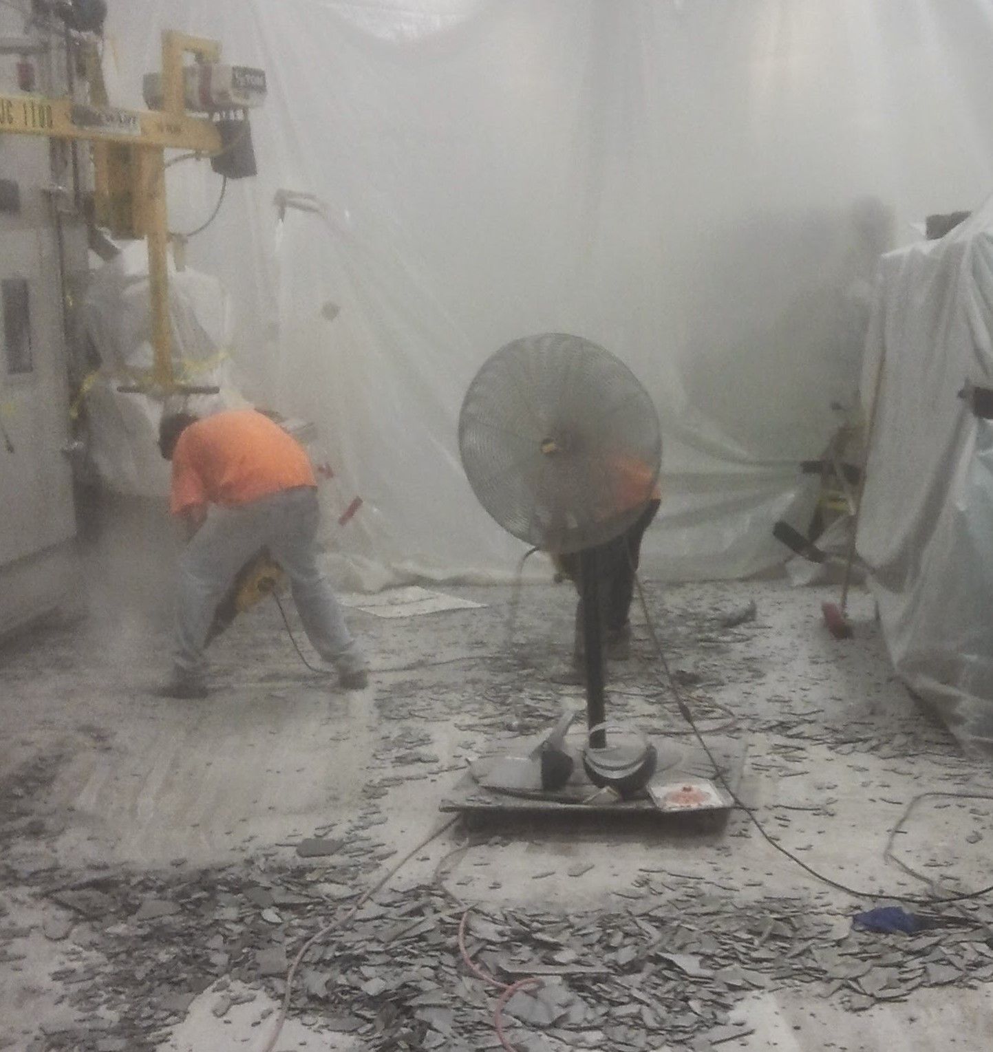 A group of people are working in a room with a fan.