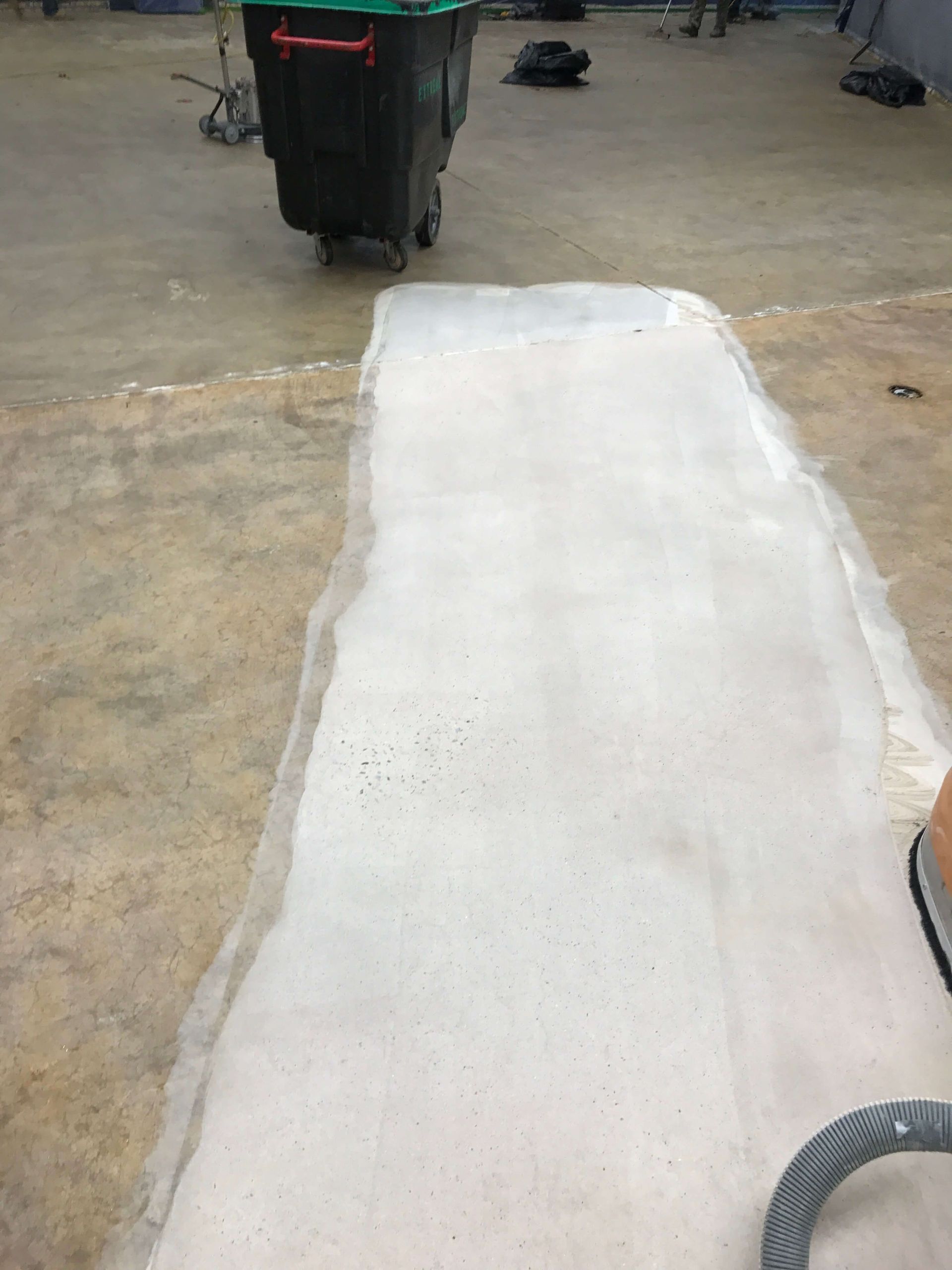 A person is cleaning a concrete floor with a vacuum cleaner.