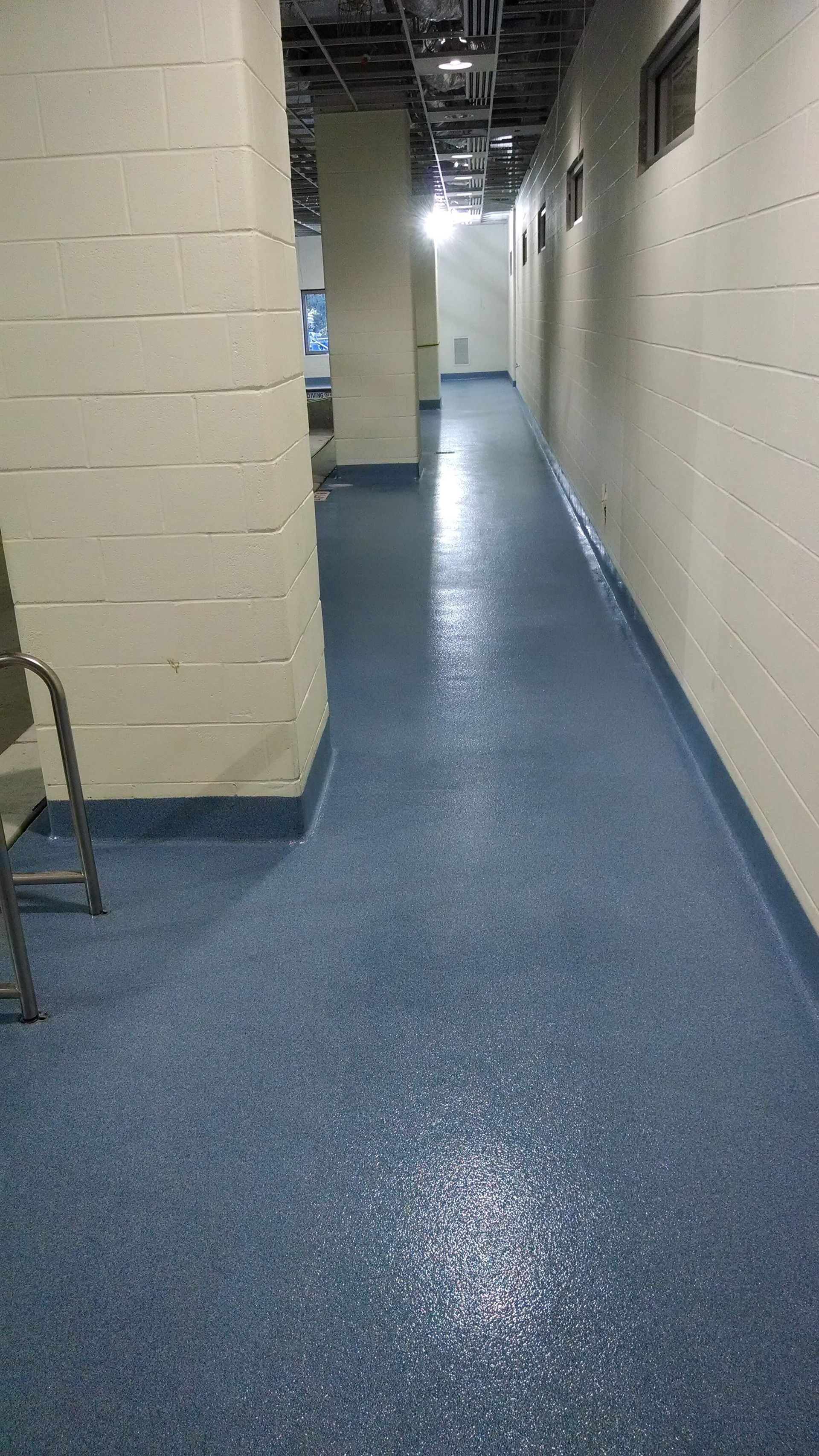 A long hallway with a blue floor and white walls.
