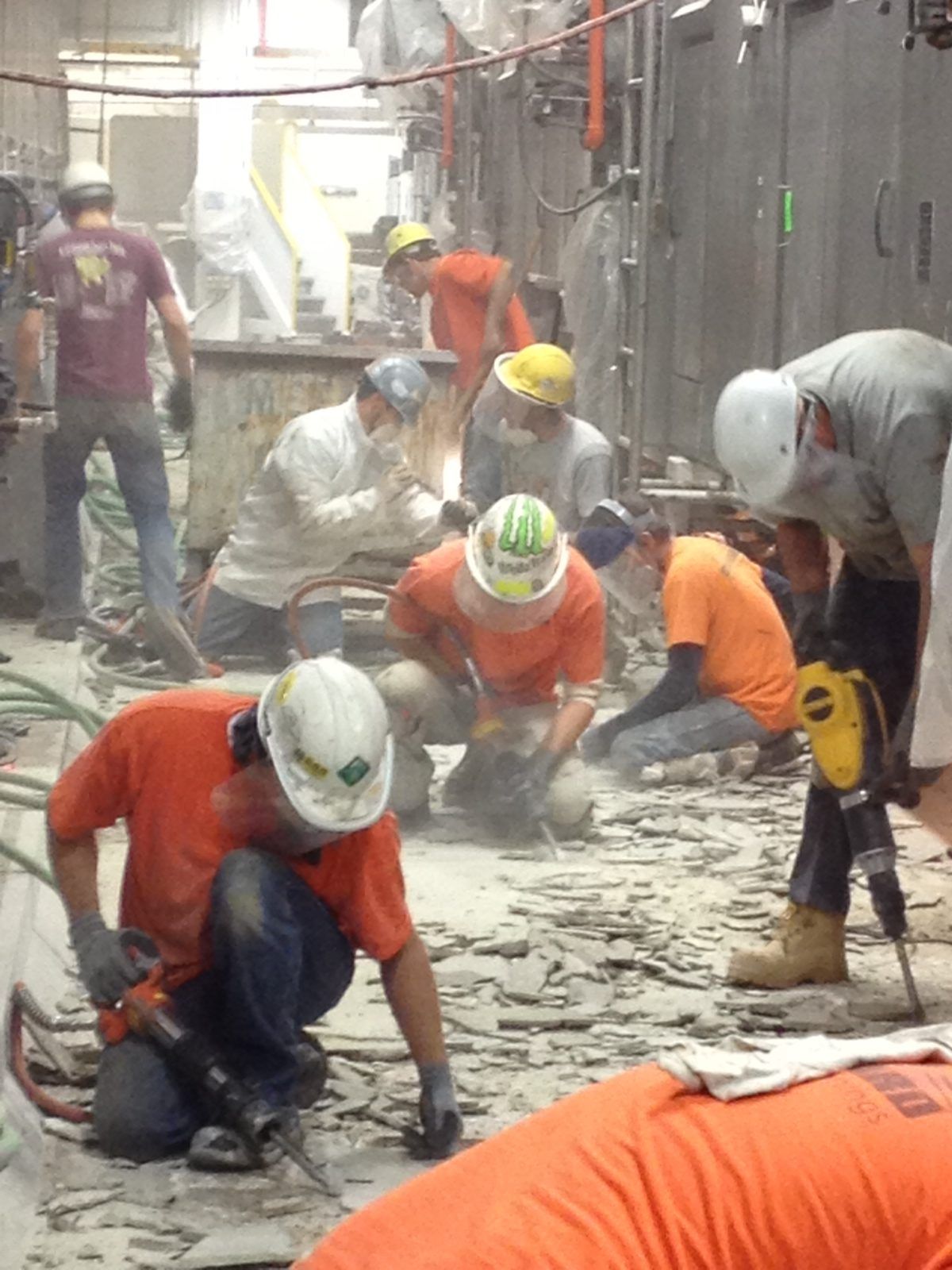 A group of construction workers wearing hard hats and orange shirts