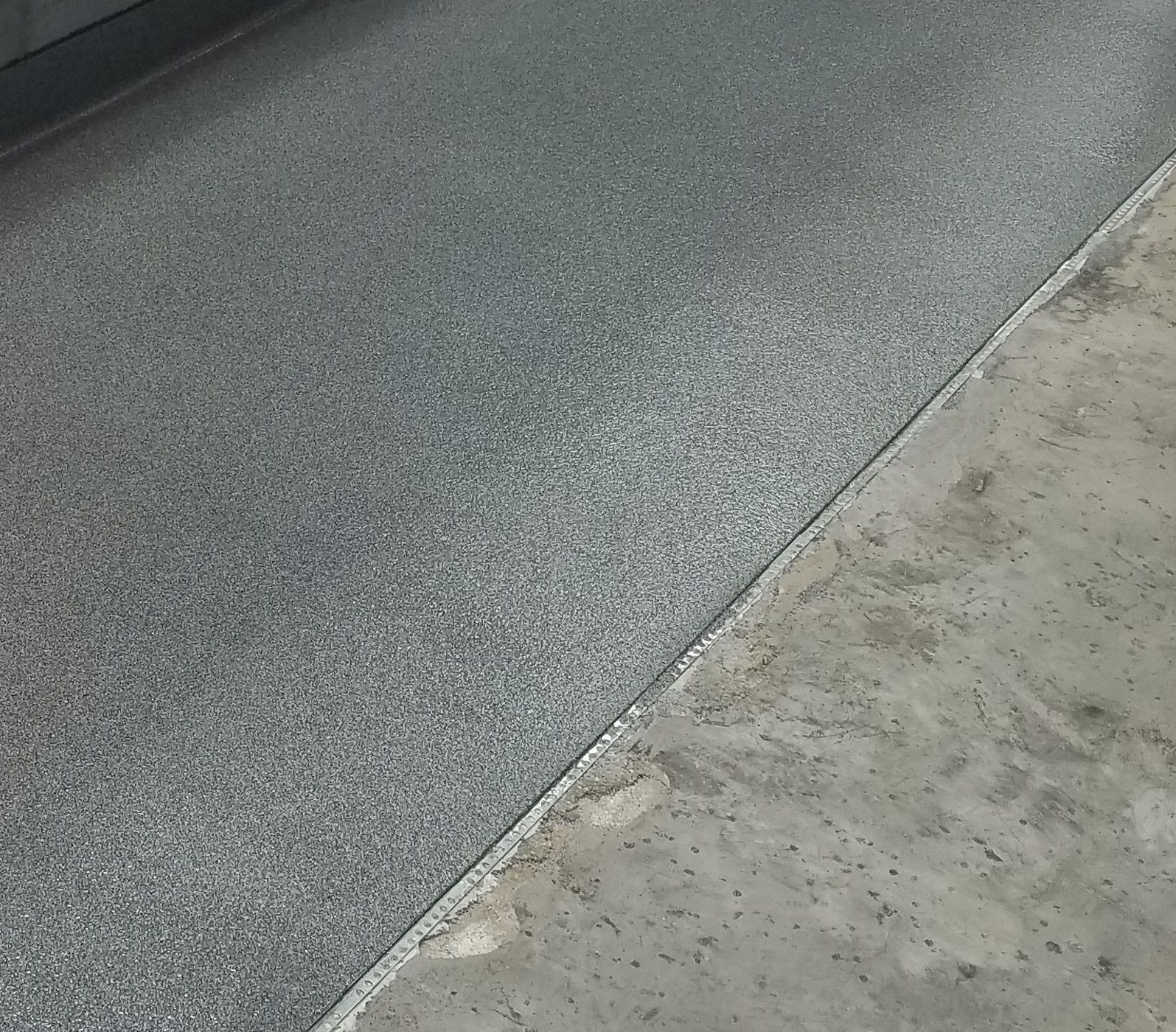 A close up of a gray concrete floor with a concrete border.