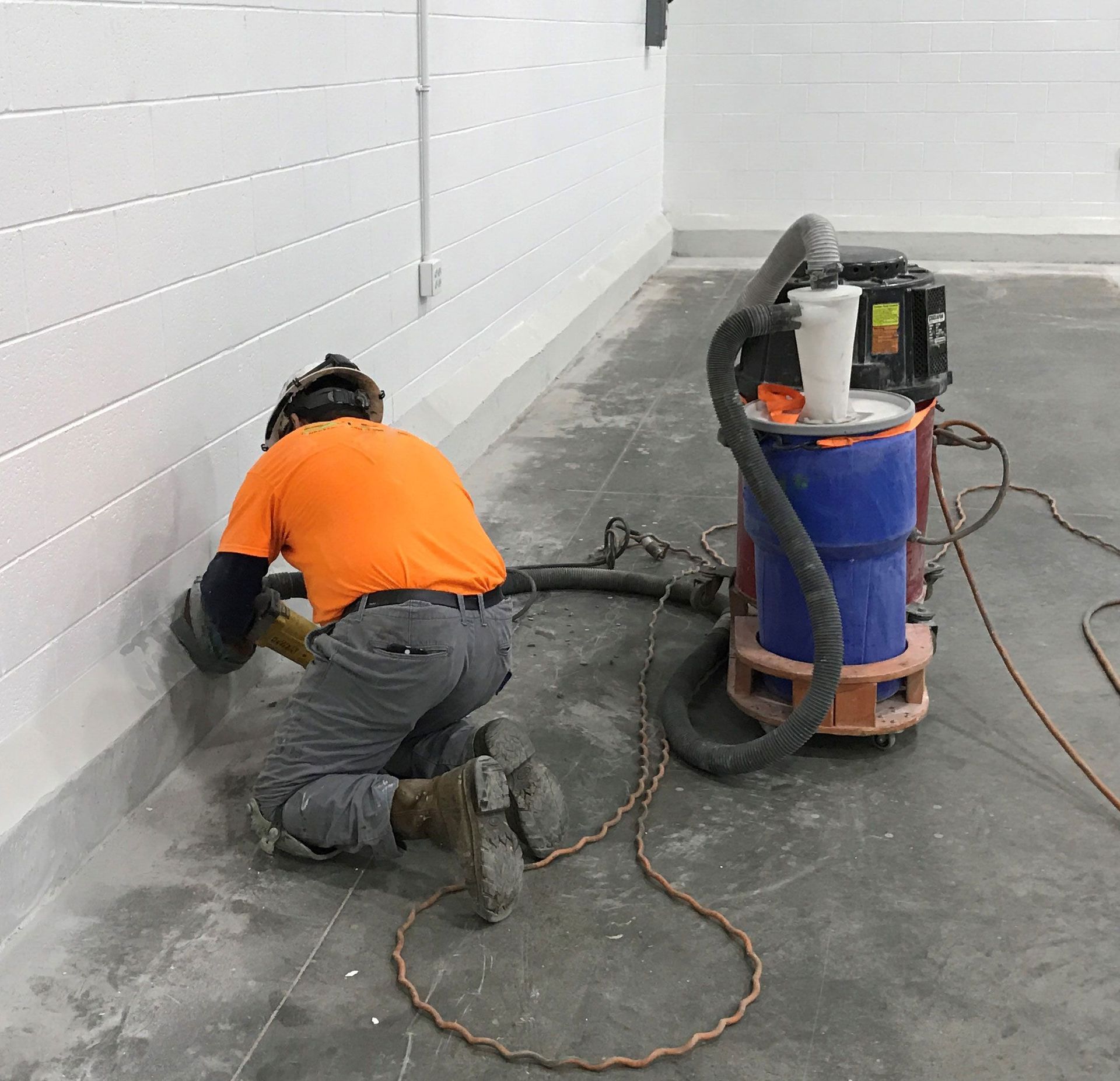 A man is kneeling down next to a vacuum cleaner