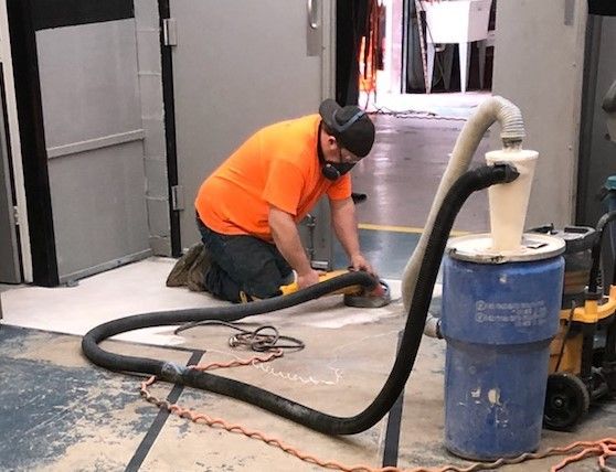 A man in an orange shirt is using industrial vacuum cleaner