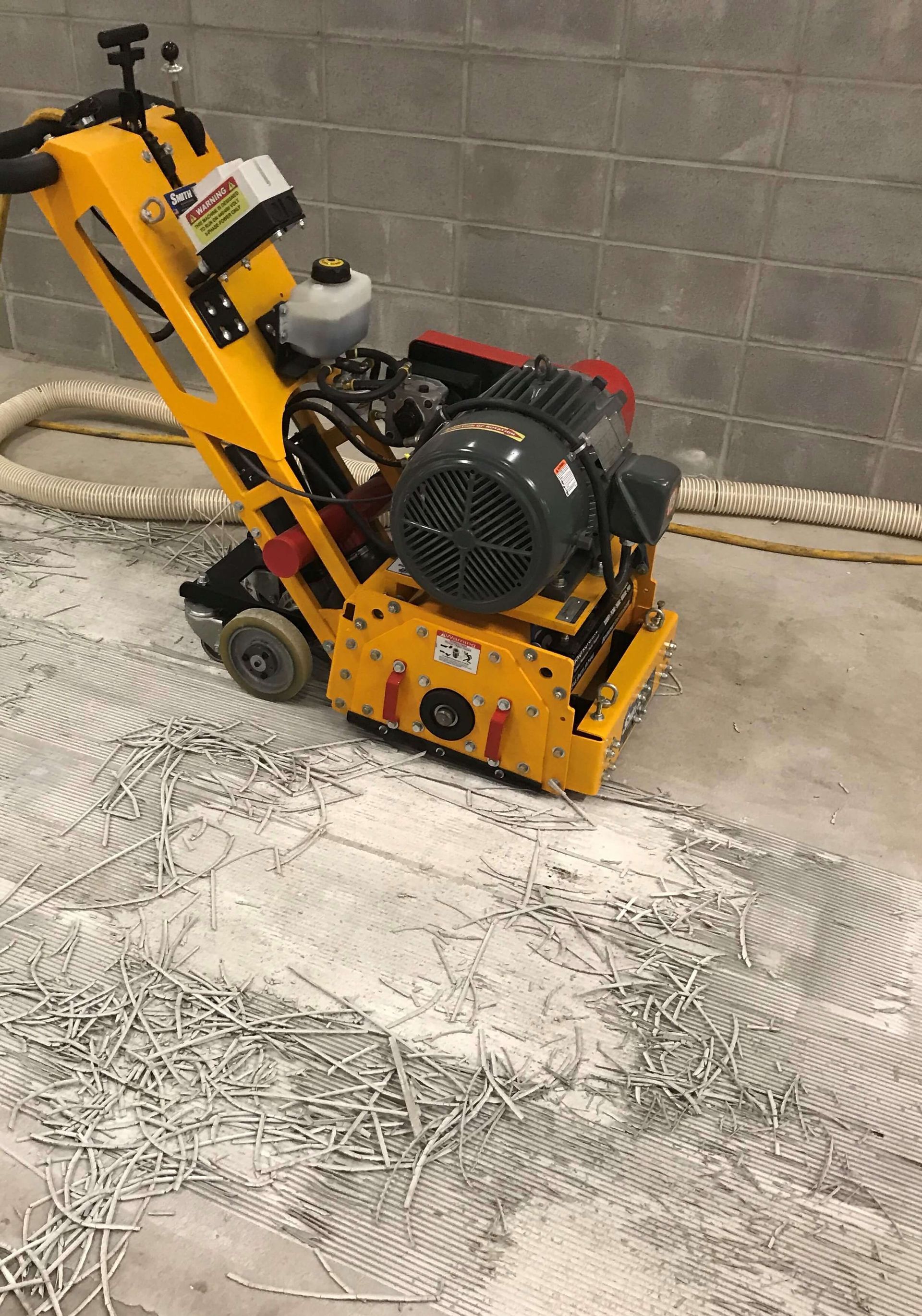 A yellow machine is sitting on top of a concrete floor.