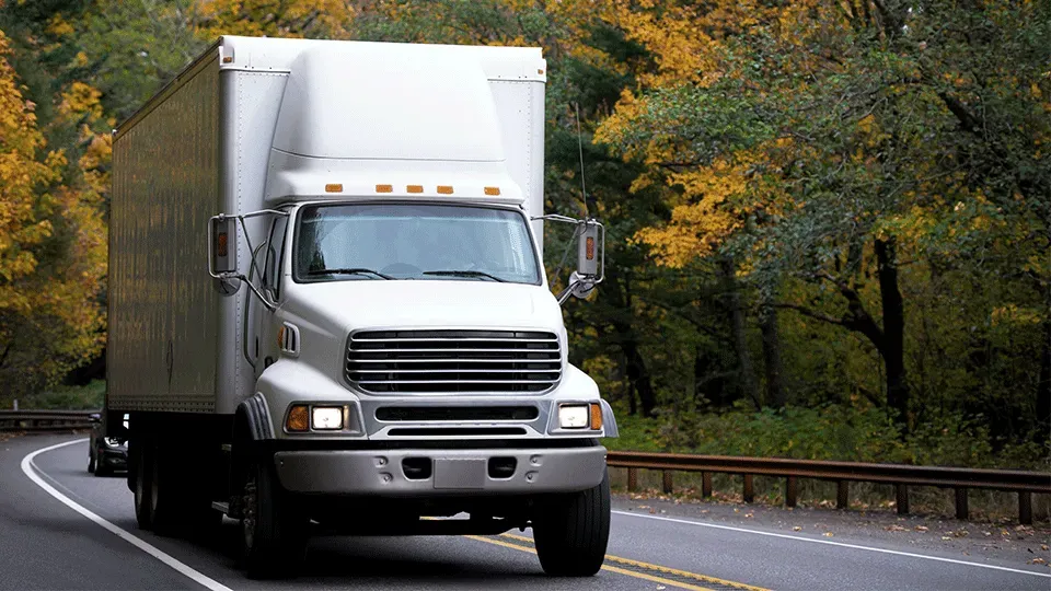 A white moving truck is driving down a highway.