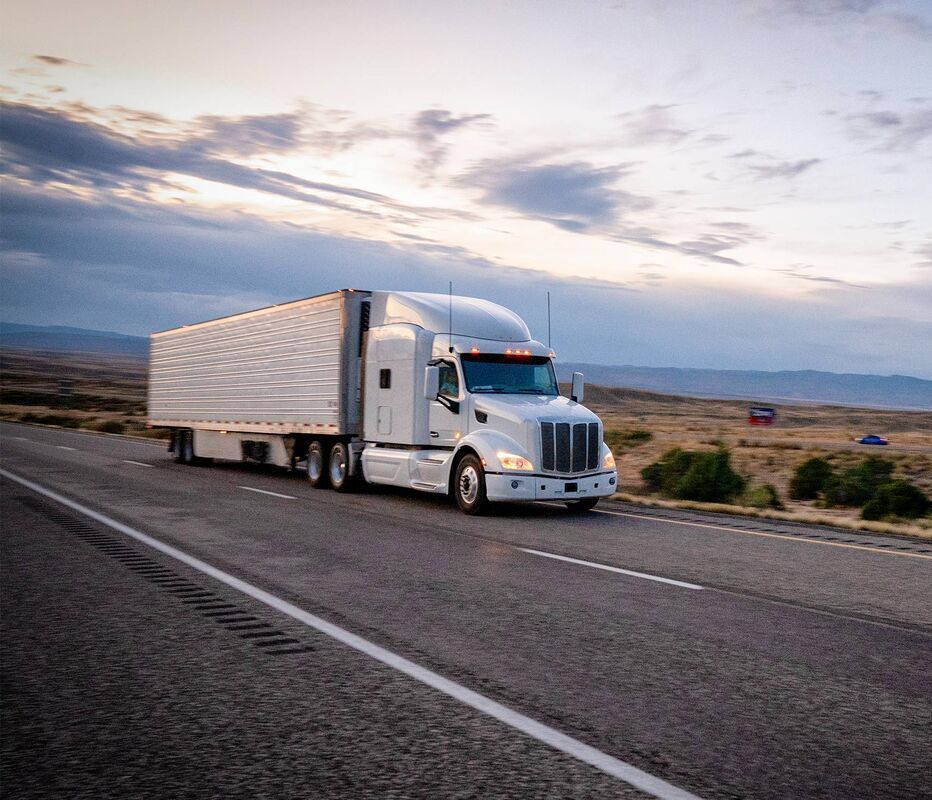 A white semi truck is driving down a highway.