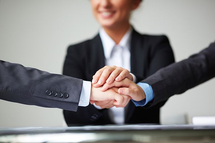 A group of business people are putting their hands together.