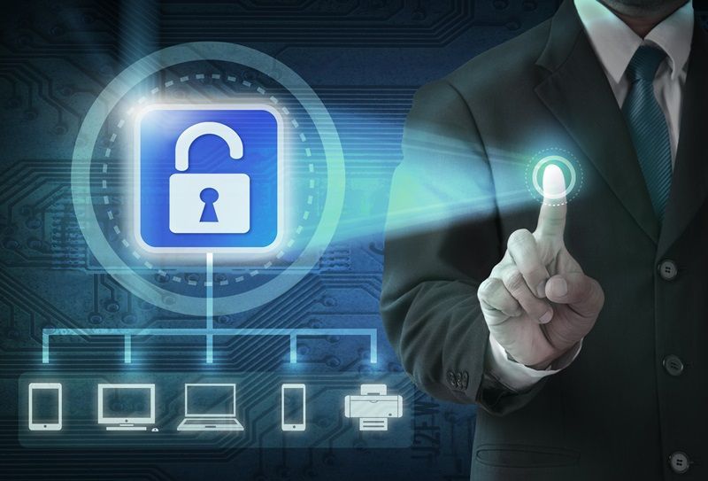 Businessman pressing a glowing security icon with network device symbols on a blue digital background