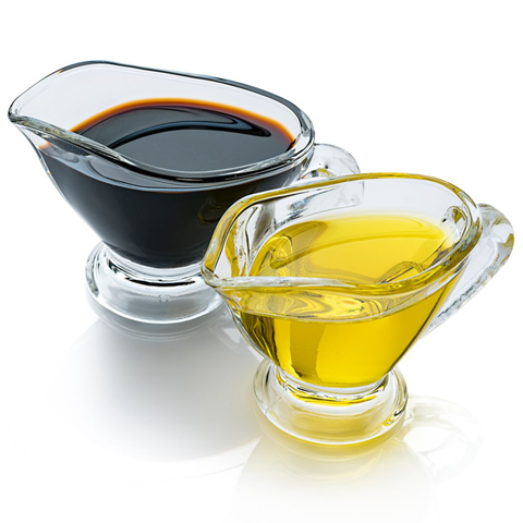 Two glass sauce boats, one with balsamic vinegar and one with olive oil