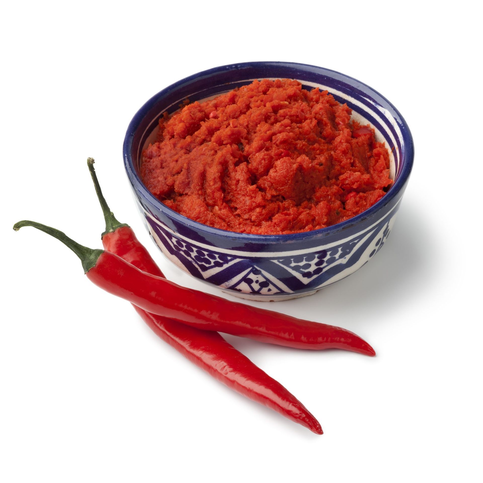 bowl of Harissa chili paste with two red chili peppers