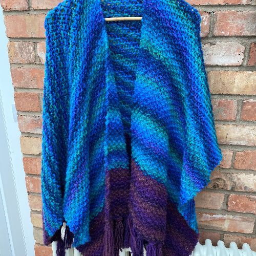 Knitted wrap in blue and purple variegated yarn; wool and acrylic blend.