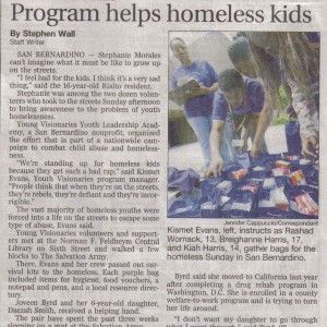 Newspaper article titled “Program helps homeless kids” with a photo of people sorting donated clothing.