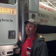 A person wearing a baseball cap and a red shirt stands next to a truck with 