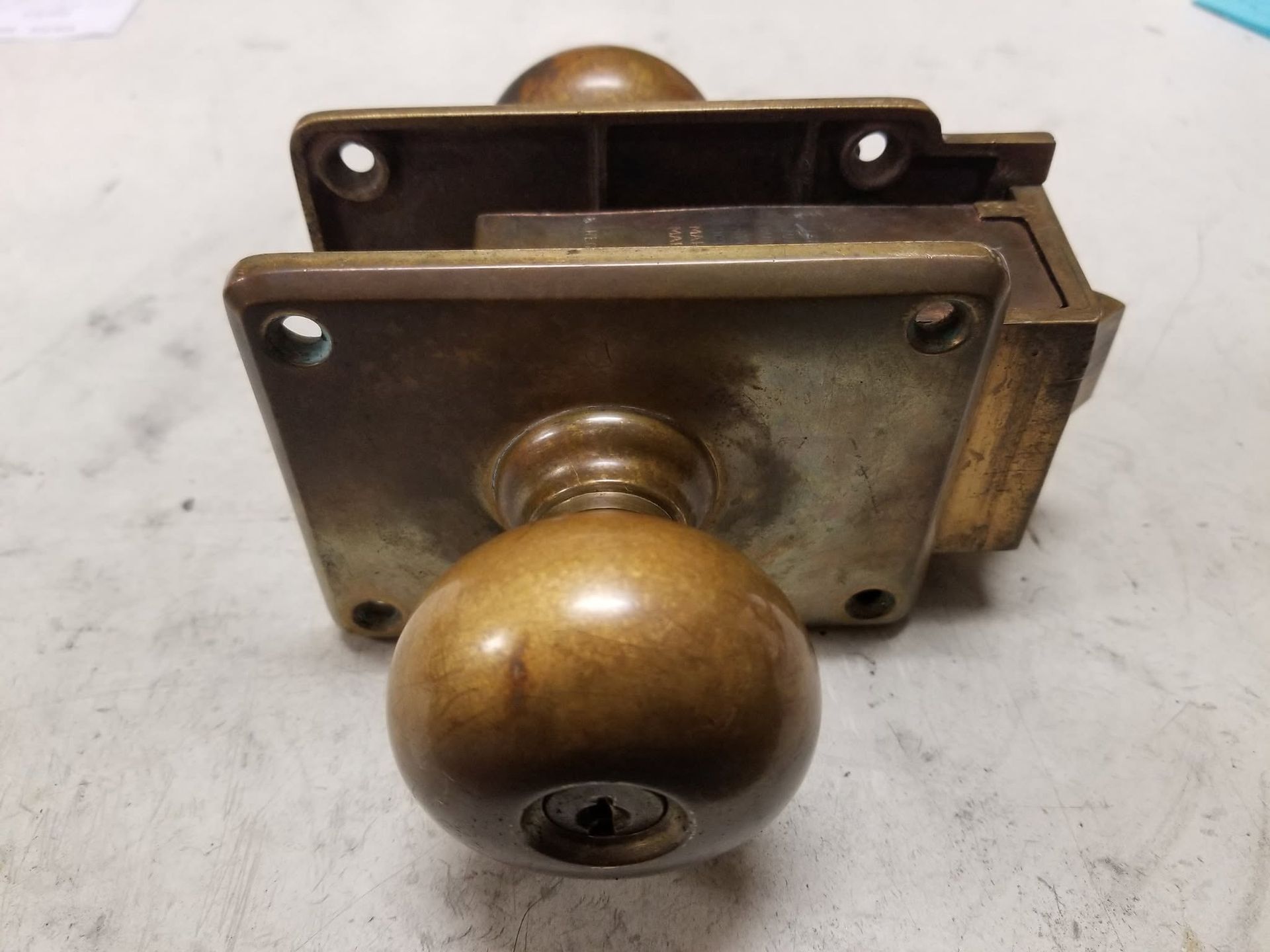 Brass doorknob and lockset on a metal plate, viewed close up.