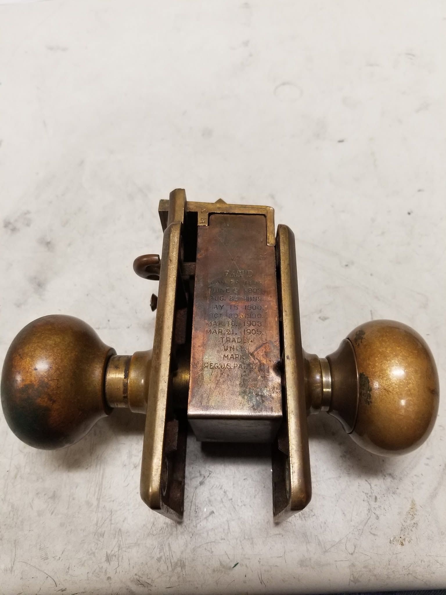 Vintage brass door latch with two round knobs on a white background