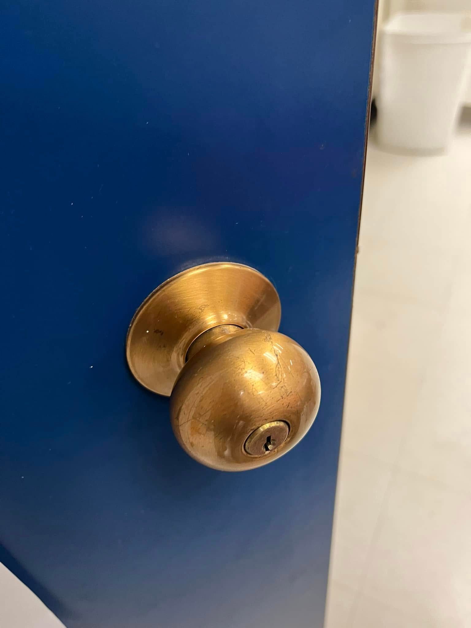 Brass doorknob on a blue door with a white wall in the background