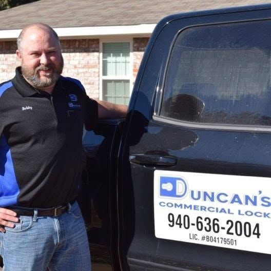 Man standing by a black service truck with a Duncan’s Commercial Lock sign and phone number