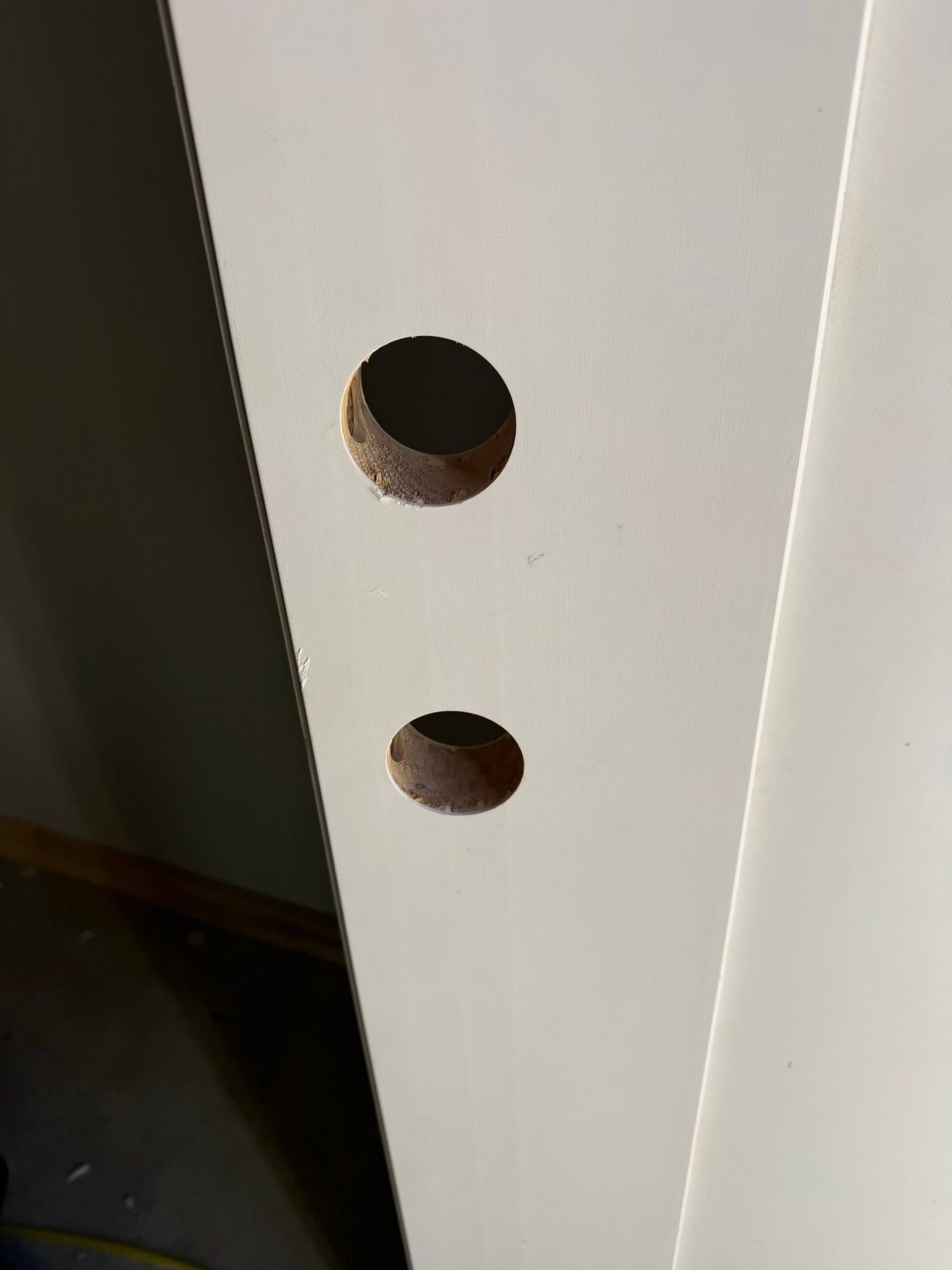 White panel with two circular drilled holes near the edge