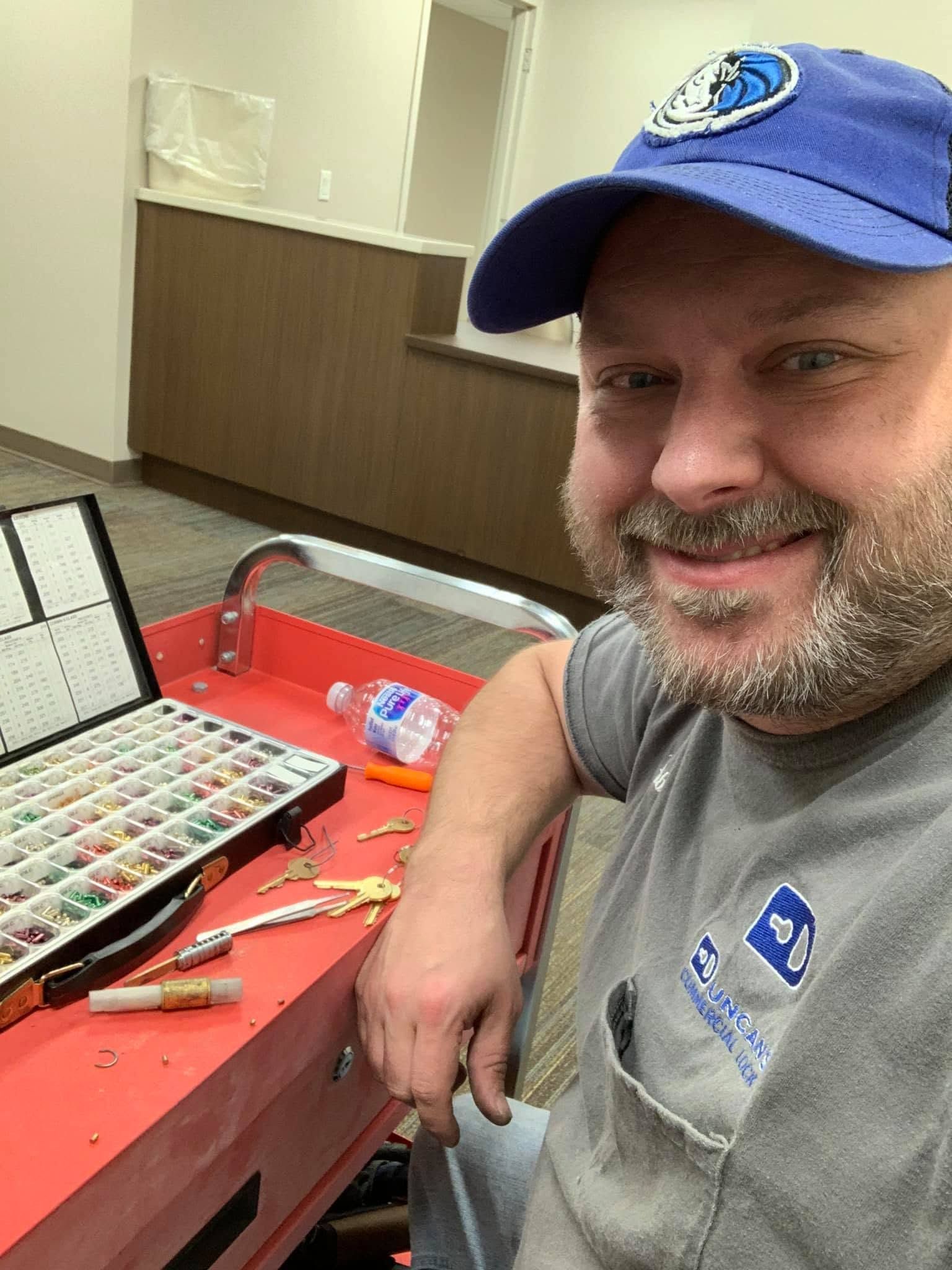 Smiling man in a blue cap beside a red workbench with tools and paint supplies