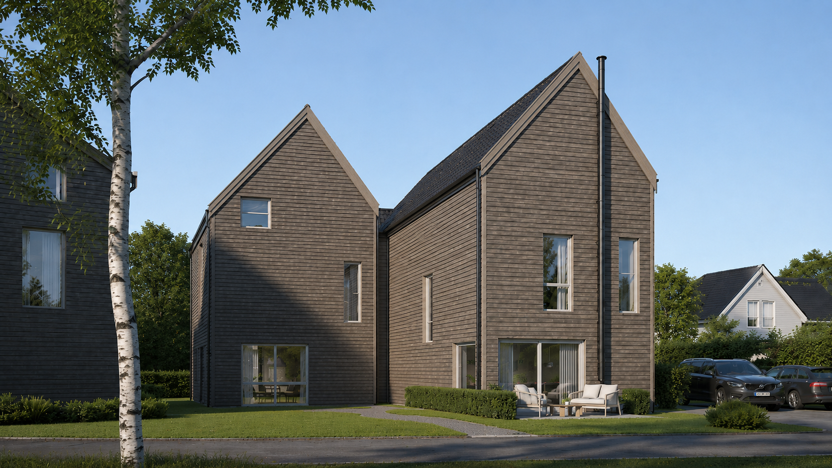 To moderne trehus med bratte tak og parkerte biler langs en rolig gate