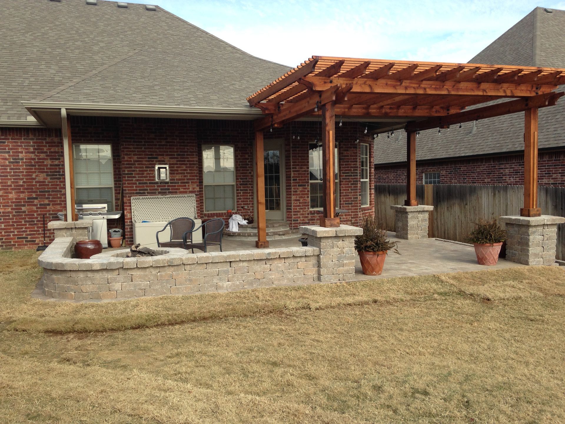 A brick house with a wooden pergola over a patio