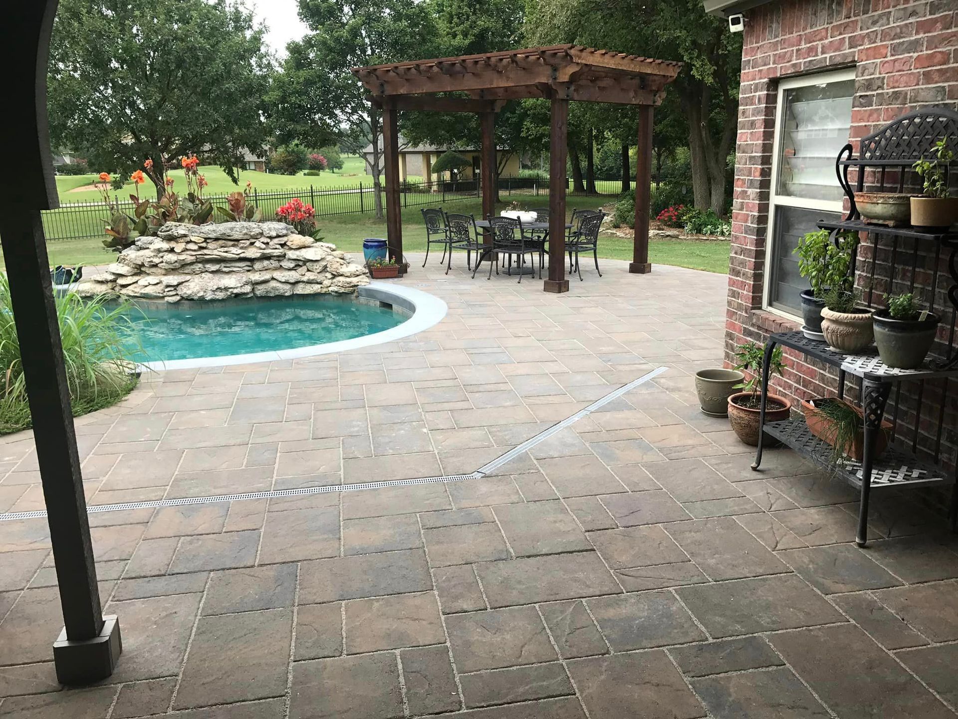 A patio with a table and chairs and a pool in the background.