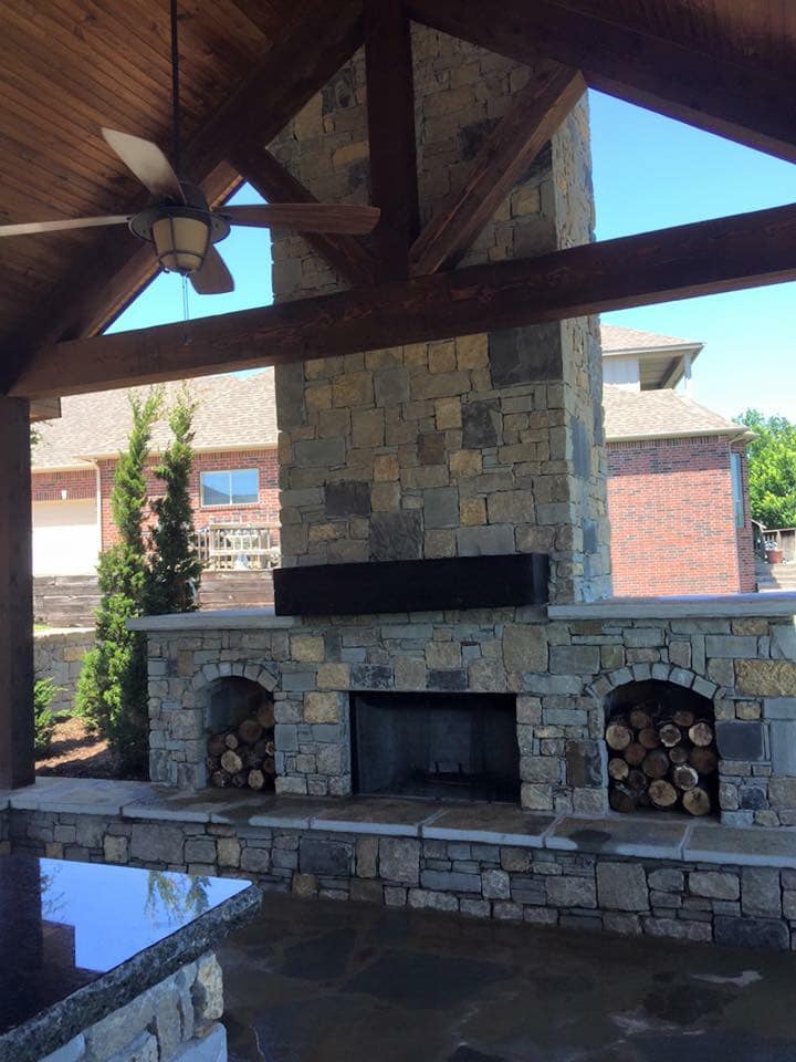 A stone fireplace with a ceiling fan above it