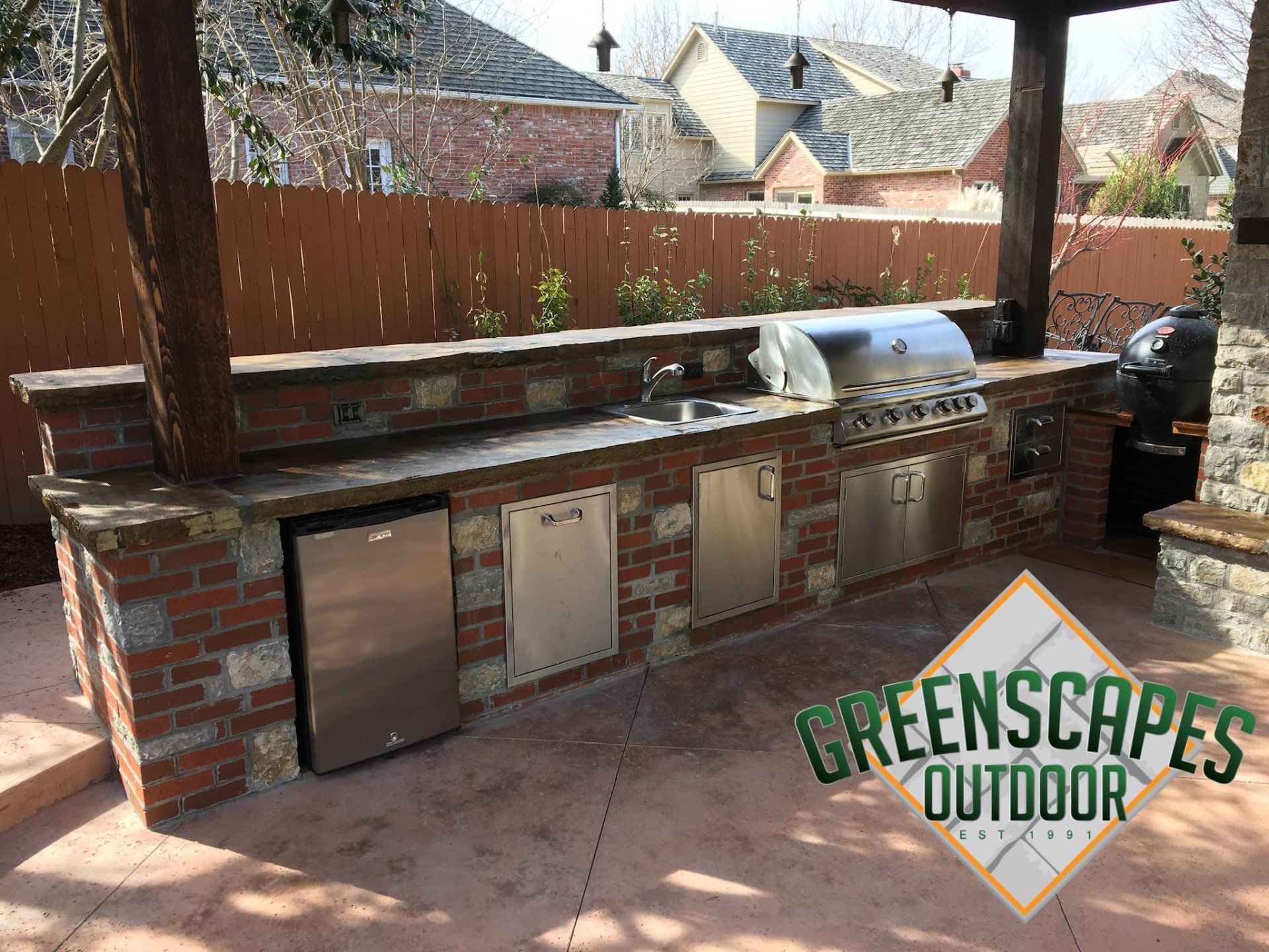 A brick outdoor kitchen with a grill and a dishwasher