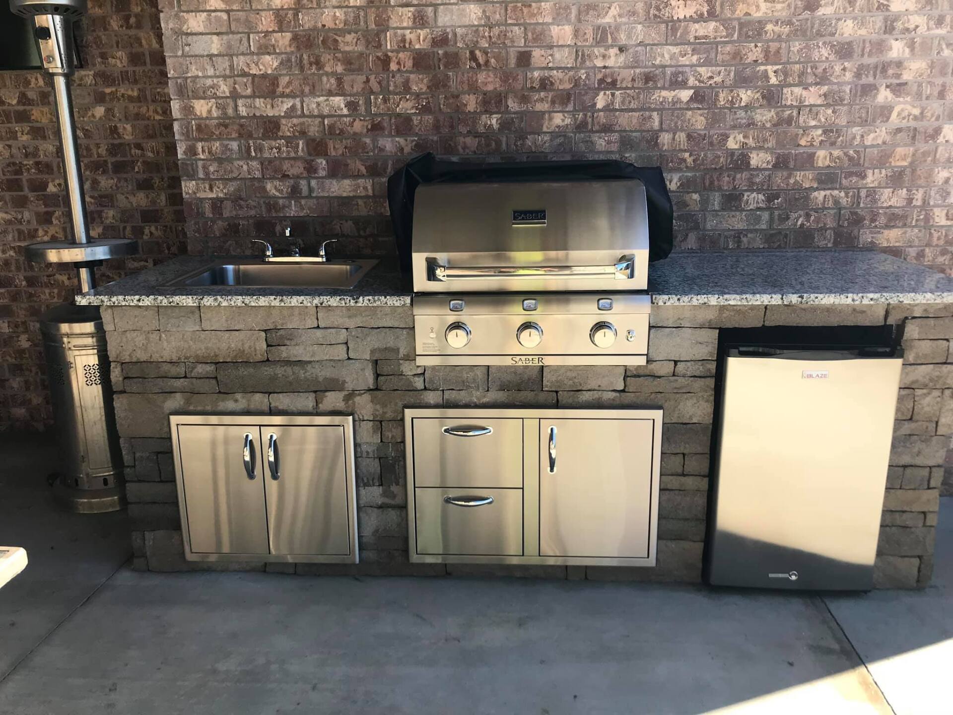 An outdoor kitchen with a grill and a sink