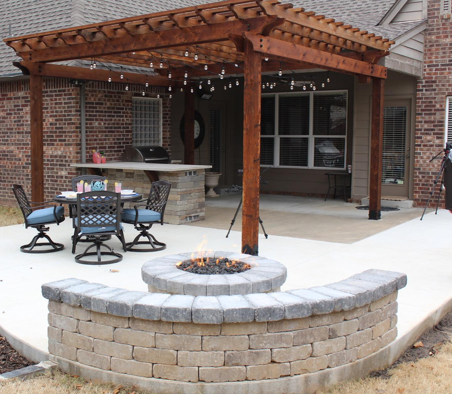 A patio with a fire pit and tables and chairs under a pergola