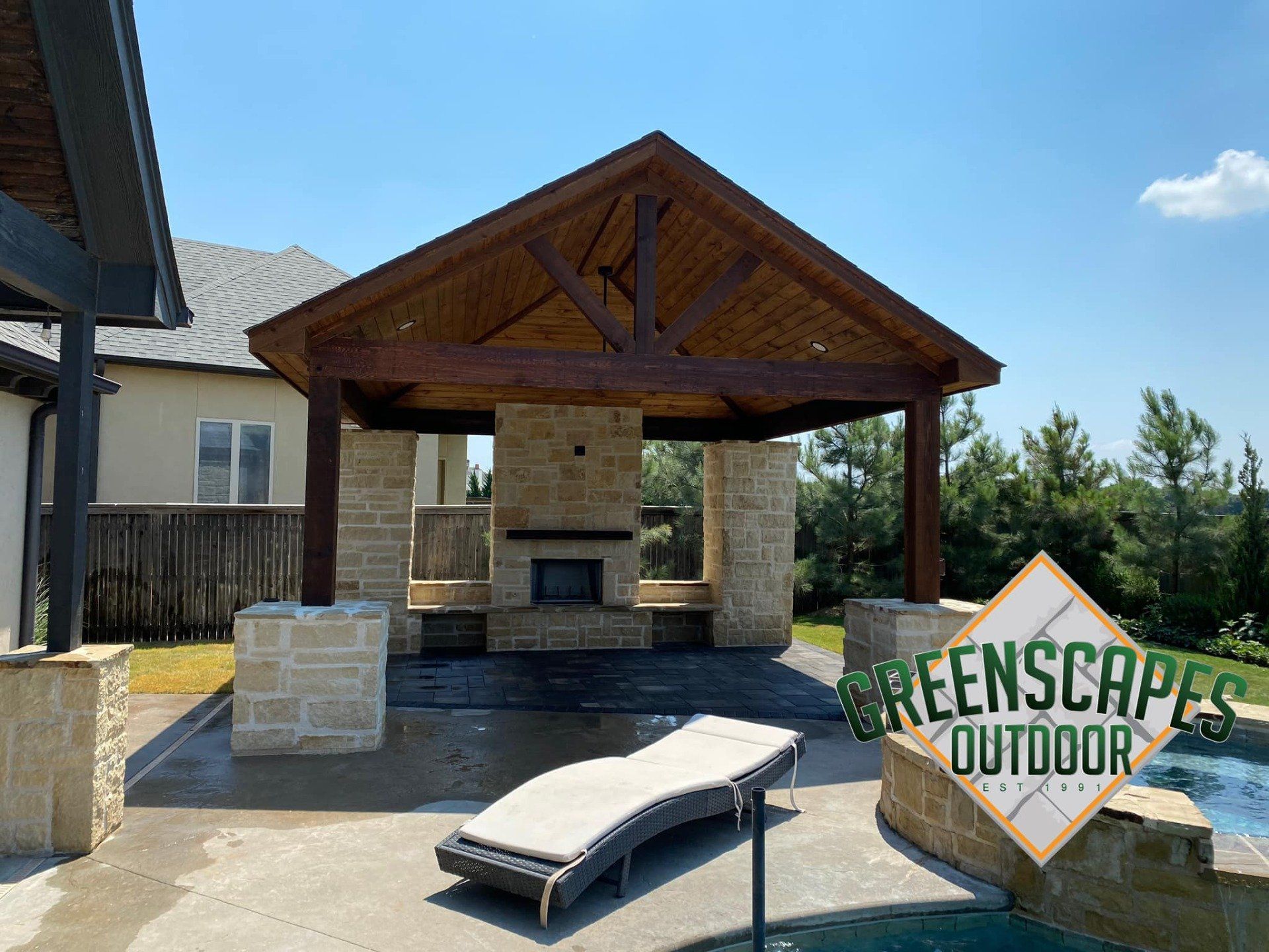 A patio with a pavilion and a fireplace next to a pool.