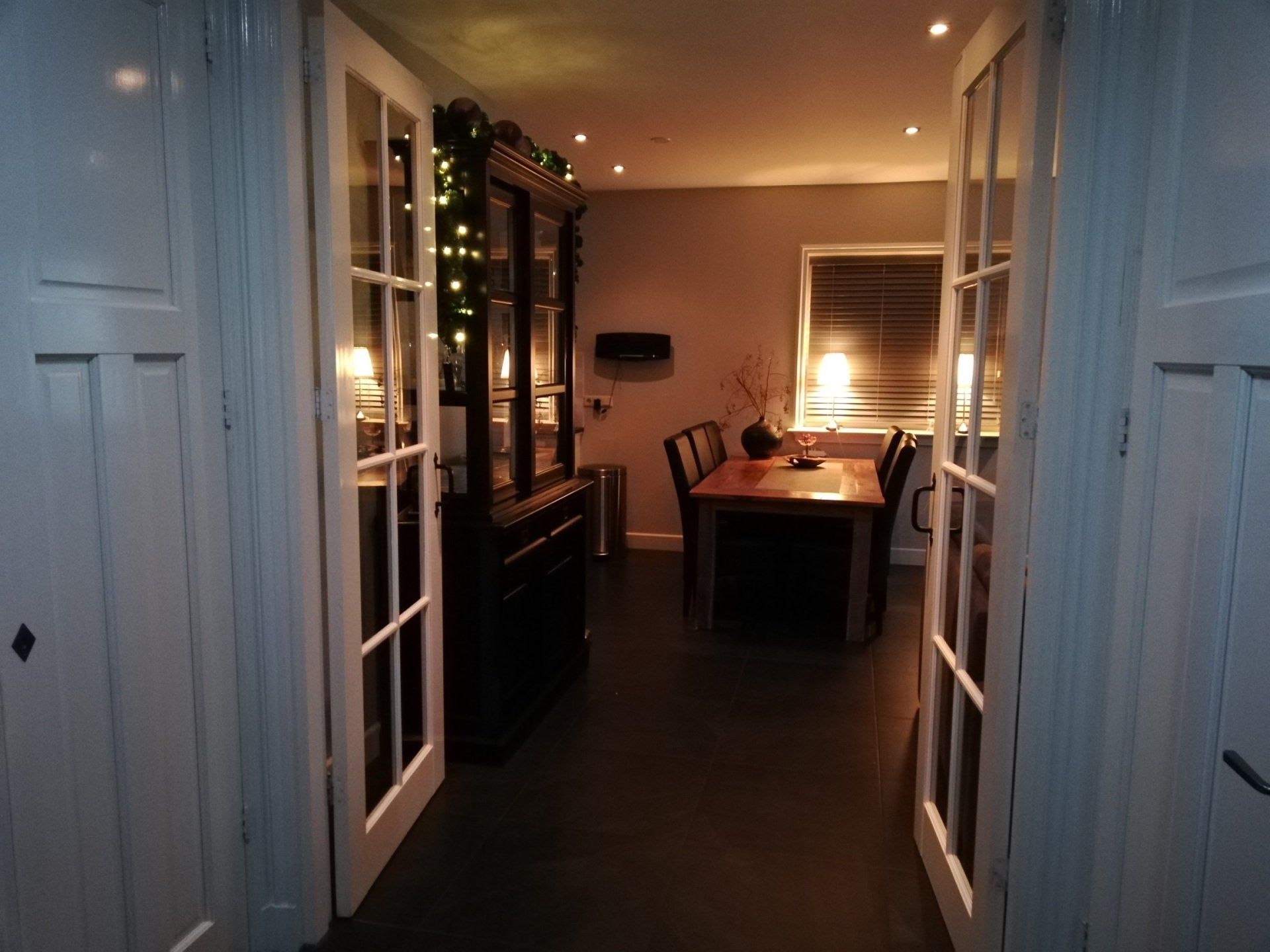Open deuropening naar de eetkamer met een donkerhouten kast en een gedekte tafel.