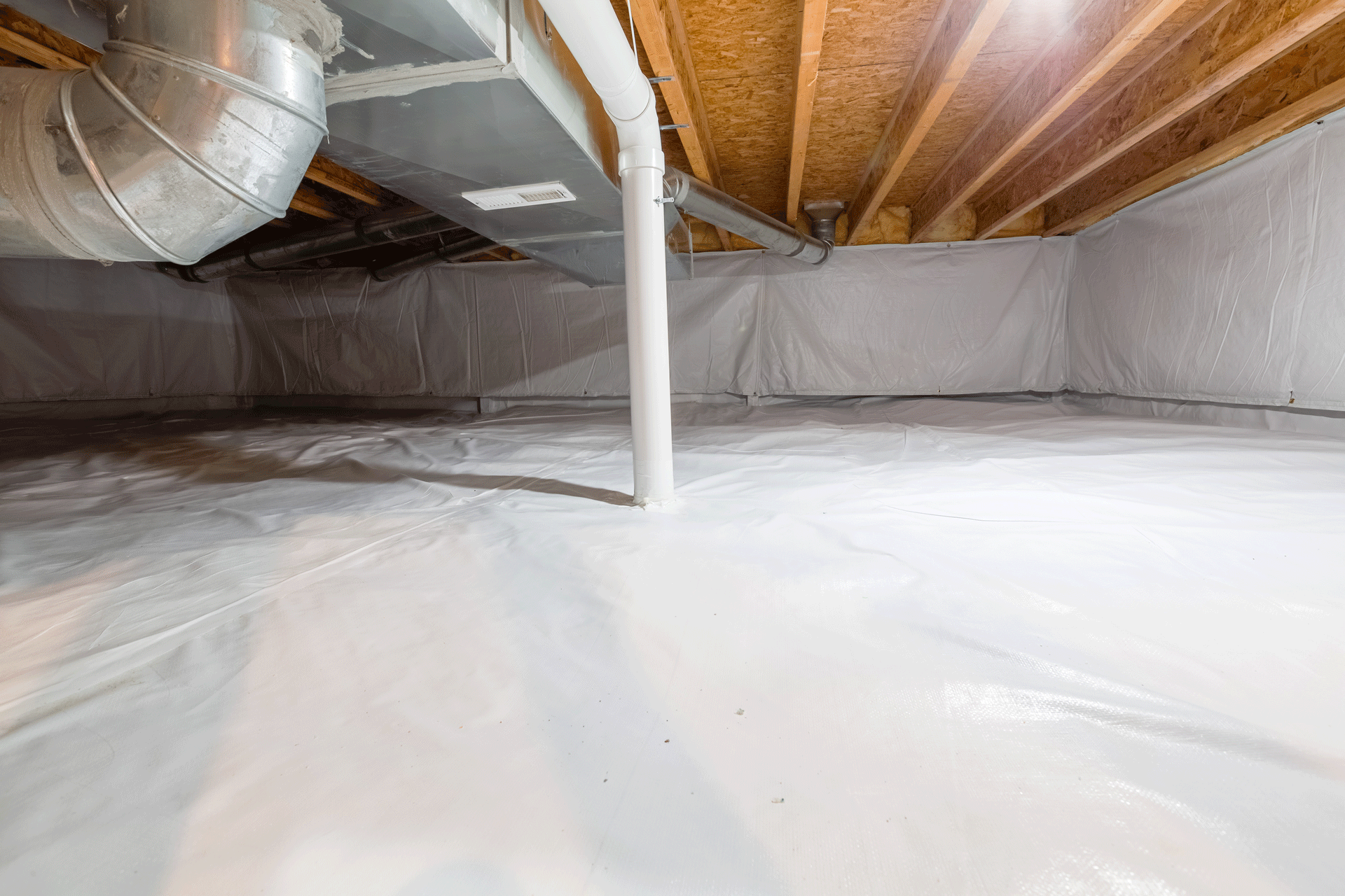 White-lined crawlspace with ductwork, plumbing, and exposed wooden joists overhead.