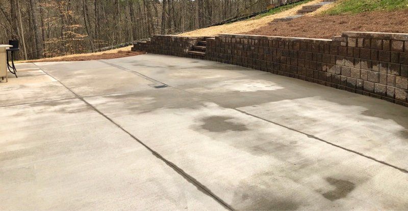 A concrete driveway with a stone wall in the background.