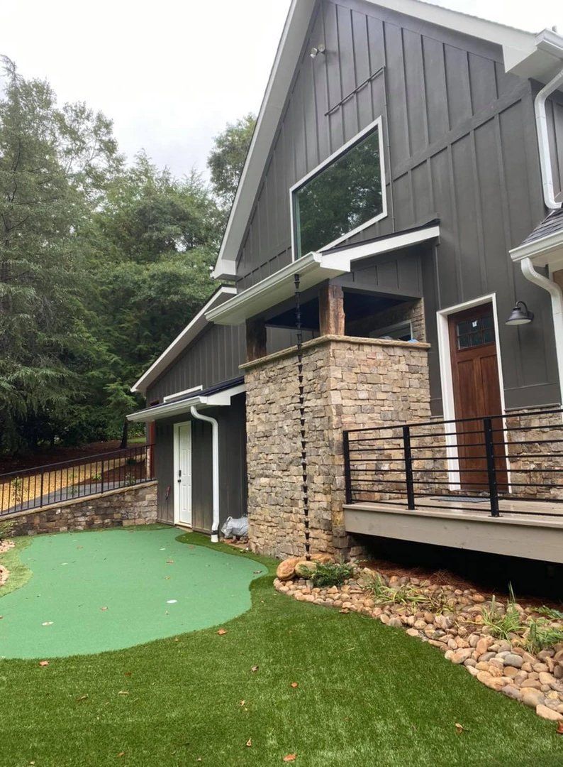 A large house with a green putting green in front of it.