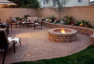 Backyard patio with stone fire pit, outdoor seating, and landscaped garden along a curved wall