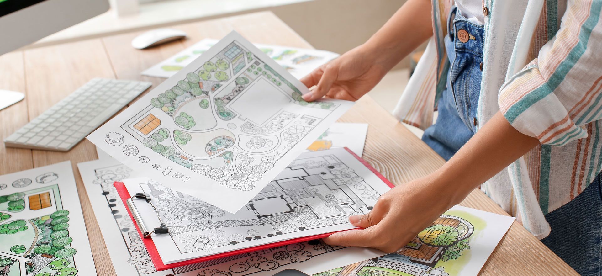 Hands arranging printed map sheets on a table in a bright workspace