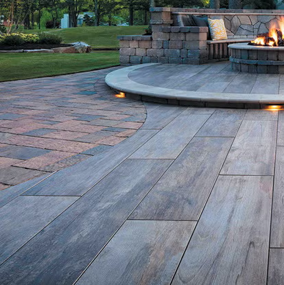 Backyard patio with gray pavers, black chairs, a bench, and a house exterior on a sunny day