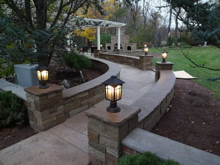Curved stone walkway with lantern posts through a landscaped garden at dusk