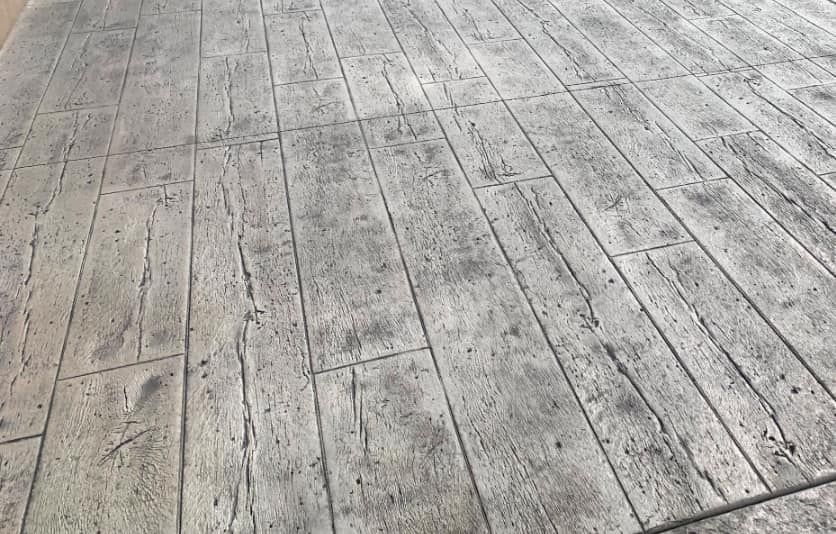Gray stamped concrete patio with a wood plank pattern.