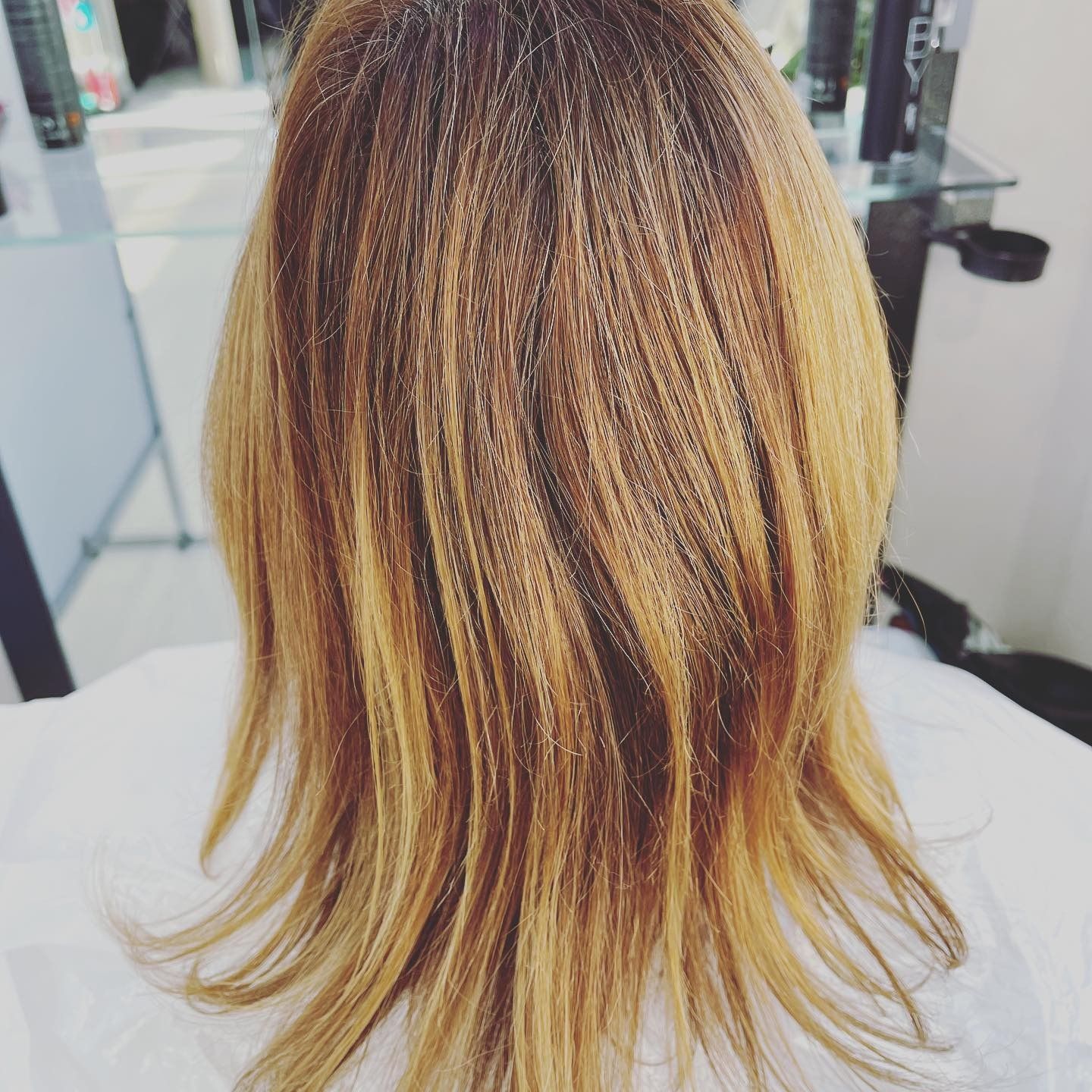 Donna con capelli biondi e castani scalati in un salone.