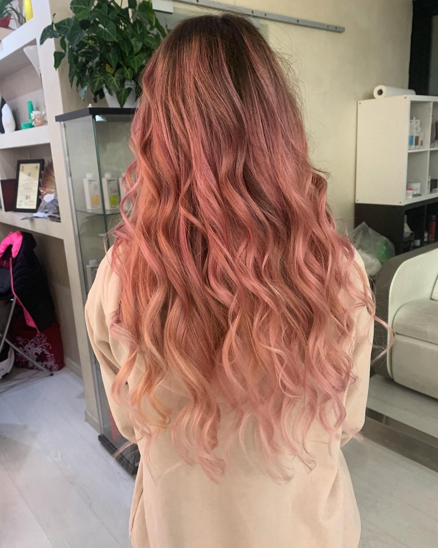 Donna con lunghi capelli ondulati color rosa e rosa in un salone.
